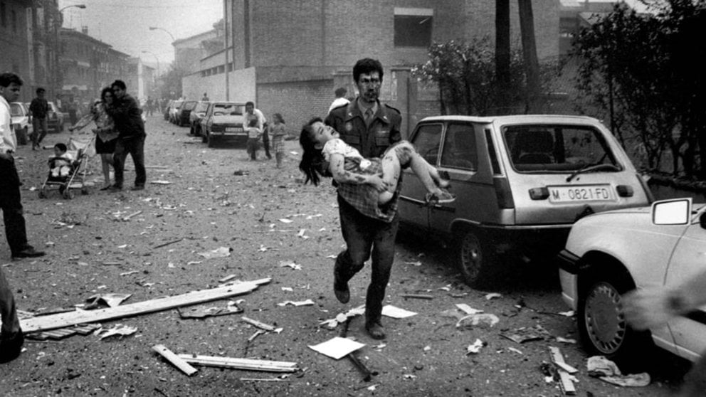 Un agente de la Guardia Civil ensangrentado, José Gálvez Barragán, lleva en brazos a una niña herida en el atentado contra la Casa Cuartel de Vic./ PERE TORDERA