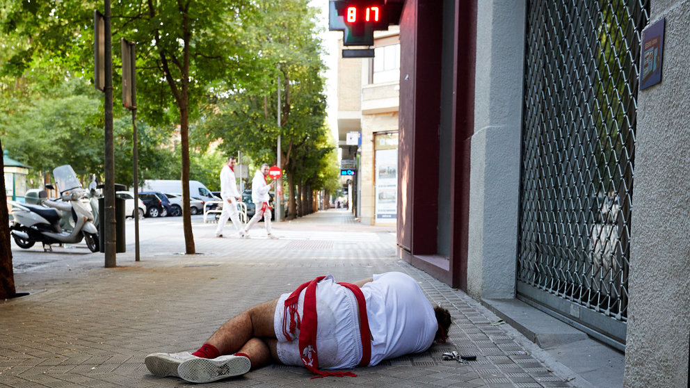 Un joven duerme en la calle minutos después del segundo encierro de San Fermín 2023. IÑIGO ALZUGARAY