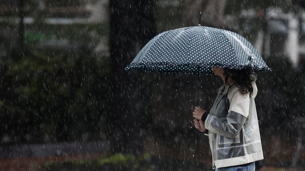 Una mujer se protege de la lluvia con un paraguas en una jornada donde el ambiente inestable, con chubascos localmente fuertes y de cierta intensidad continúa en la Comunidad Foral.  EFE/ Jesús Diges