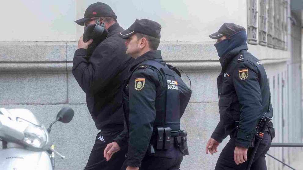 Koldo García, tapado por una gorra y custodiado por dos agentes de Policía a su salida de la Audiencia Nacional. EUROPA PRESS
