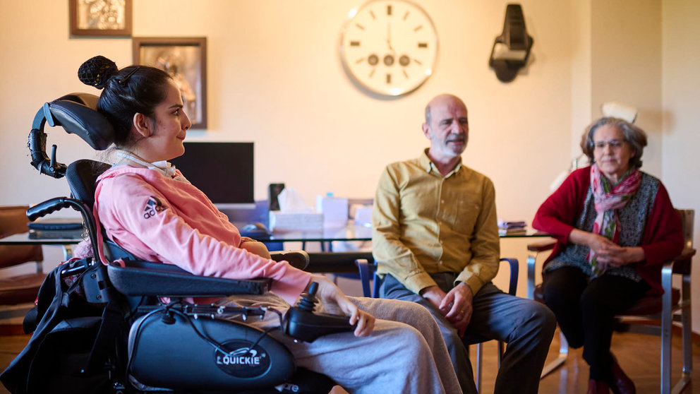 Marina Sacristán, en su silla de ruedas después de sufrir un íctus en 2027 cuando tenía 17 años, junto a sus padres Marta y José Antonio. PABLO LASAOSA